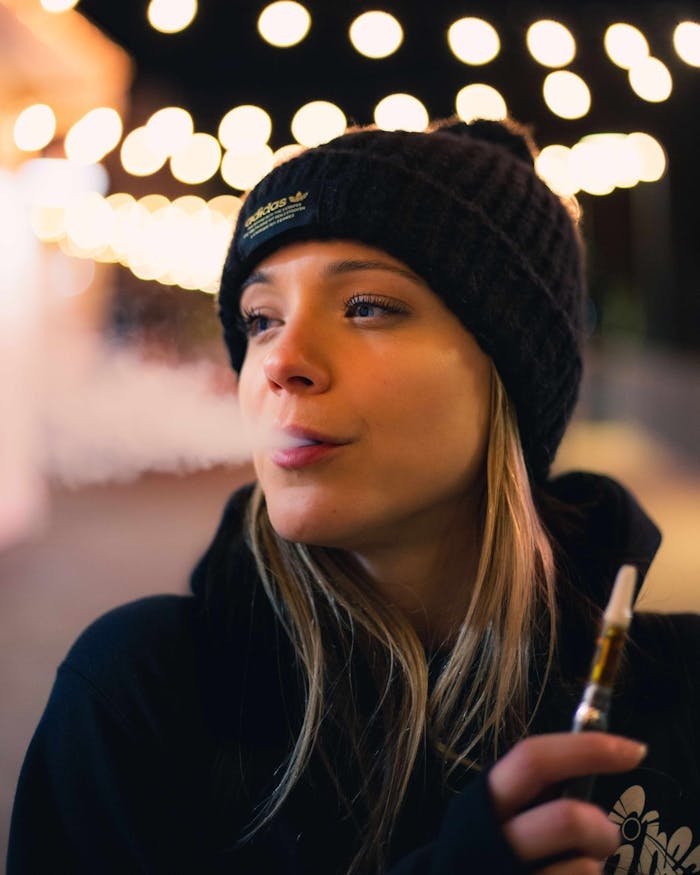 why-choose-us Young woman enjoying vaping at night with city lights in the background, Sacramento, CA.